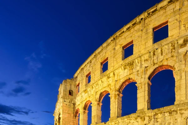 The ruins of the Colosseum in Rome, Italy. The Colosseum against the background of the sky in the evening. Night illumination on the building. Ancient historical building.