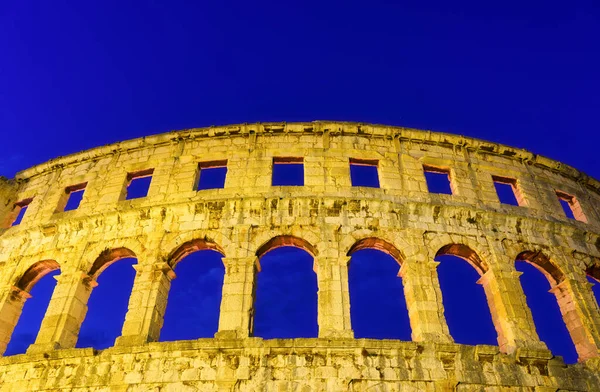 The ruins of the Colosseum in Rome, Italy. The Colosseum against the background of the sky in the evening. Night illumination on the building. Ancient historical building.