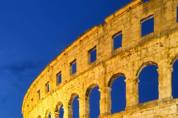 The ruins of the Colosseum in Rome, Italy. The Colosseum against the background of the sky in the evening. Night illumination on the building. Ancient historical building.