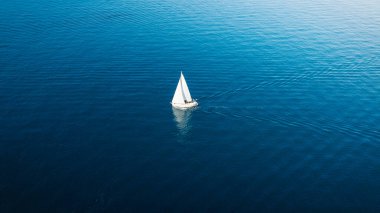 An aerial view of the sail yacht on the blue sea. Transparent clear water in the sea. Summer vacations and travels on a sailing yacht. Summer relaxation.