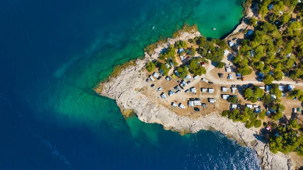 Aerial view of the camper parking area. Camping on the seashore. Resting in a mobile home. Cape and blue sea. Landscape from the air. View down from the drone.