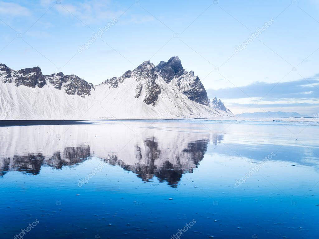 Stokksness, Vestrahorn National Park, Iceland. Wide beach with black volcanic sand. Reflections on the seashore at high tide. View of Iceland's nature in winter time.