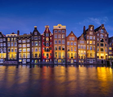 Damrak, Amsterdam, Netherlands. View of houses during sunset. The famous Dutch canals. A cityscape in the evening. Travel photography.
