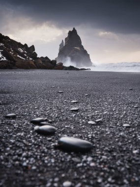 Reynisfjara, İzlanda. İzlanda 'da popüler bir mekan manzarası. Fırtına sırasında kayalar. Yüksek dalgalar. Deniz kıyısında çakıl taşları. Seyahat etmek için popüler bir yer.