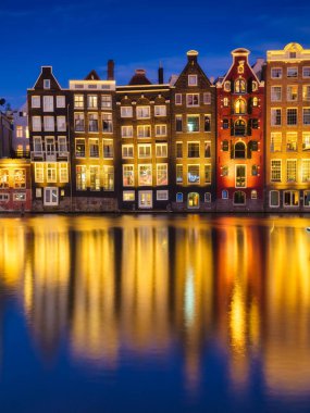 Damrak, Amsterdam, Netherlands. View of houses during sunset. The famous Dutch canals. A cityscape in the evening. Travel photography.