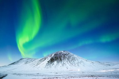 Aurora Borealis. Dağların üzerinden Kuzey Işıkları. Gökyüzünde parlak ışıklar olan bir kış gecesi manzarası. Kış zamanı kuzeyde manzara. Seyahat etmek için popüler bir yer.