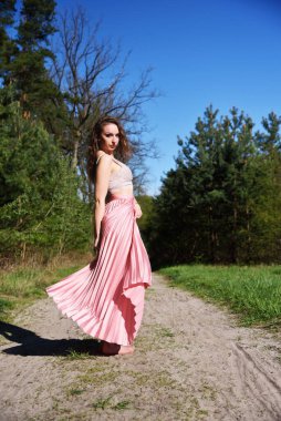 Ormanda serçe parmağıyla dönen güzel, genç bir kadın. Polonya 'da ilkbahar boyunca yeşil çevre.