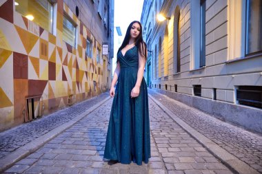 Wroclaw şehri, akşamları poz veren genç bir kadın. Esmer kadın model, uzun, yeşil elbiseli..