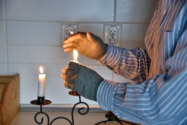 Yoksulluğun sembolleri: evde elektriksiz ve ısıtmasız bir adam. Isınmak için mum kullanıyorum..