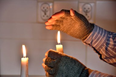 Yoksulluğun sembolleri: evde elektriksiz ve ısıtmasız bir adam. Isınmak için mum kullanıyorum..
