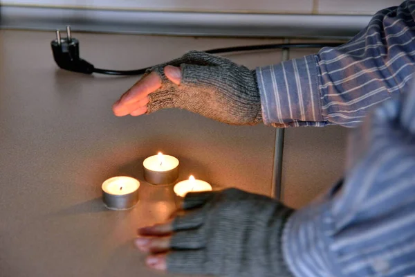 Symbols of poverty: man at home without electricity, without heating. Using candles to warm up.