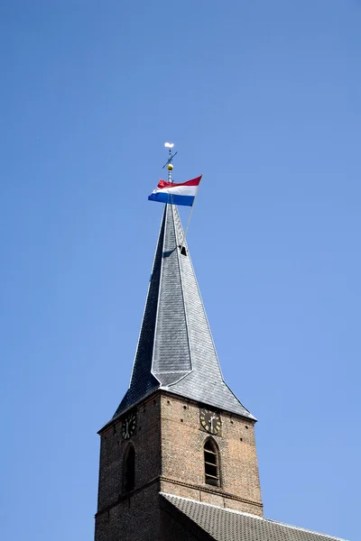 Nizozemská vlajka mávání ve větru z kostelní věže — Stock fotografie