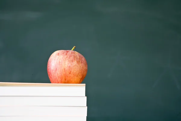 Boeken en appel met gebruikte groene schoolbord op de achtergrond — Stockfoto