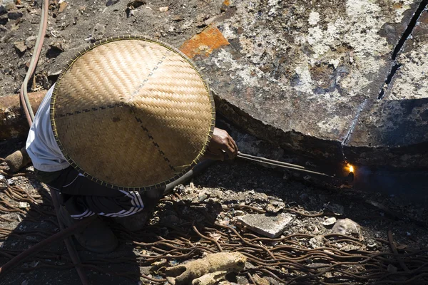 Indonesian worker cutting metal using a cutting torch — Stock Photo, Image