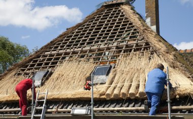 Workmen thatching a new roof clipart