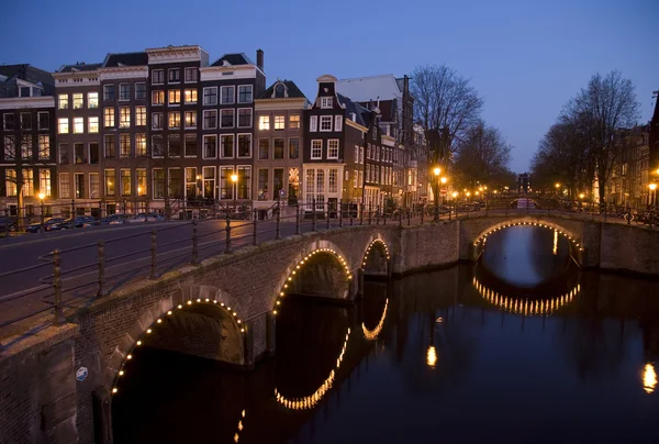 Kanalen korsning på natten i amsterdam, holland — Stockfoto