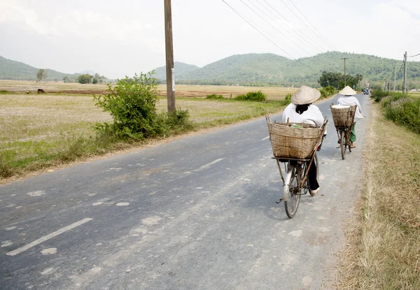 Två cyklister på en landsbygdens gata i Mekongdeltat, vietnam — Stockfoto