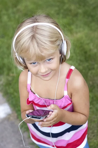 Ребенок со смартфоном и наушниками — стоковое фото