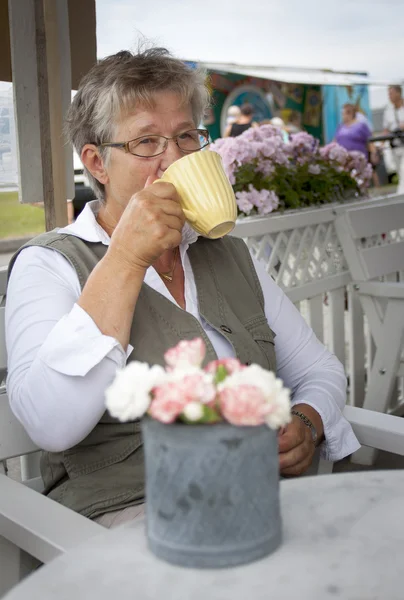 Old woman drinking coffee — Stock Photo, Image