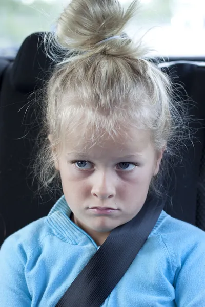 Grumpy kid with seatbelt in car — Stock Photo, Image