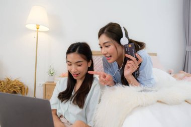 Genç Aisan çifti kitap okuyup internetten alışveriş yapıyor.