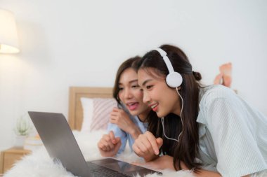 Genç Aisan çifti kitap okuyup internetten alışveriş yapıyor.