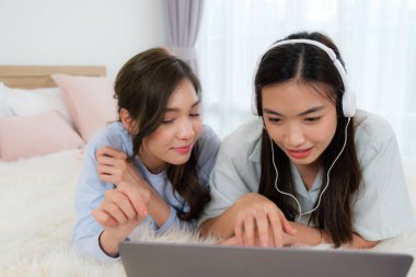 Genç Aisan çifti kitap okuyup internetten alışveriş yapıyor.