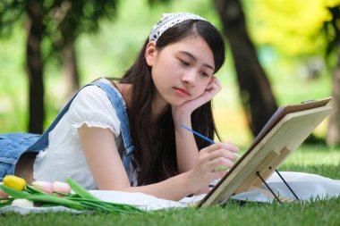 Genç Asyalı kadın parkta piyano çalıyor ve dinleniyor..