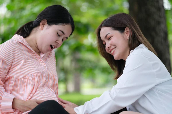 Pregnant woman hangout with her friend relaxing in the garden