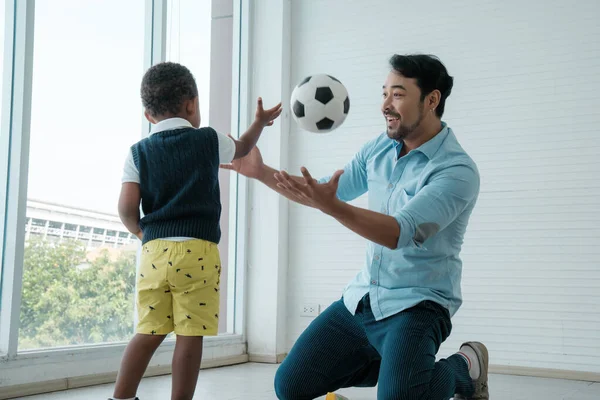 Daddy and son enjoy playing football together at home