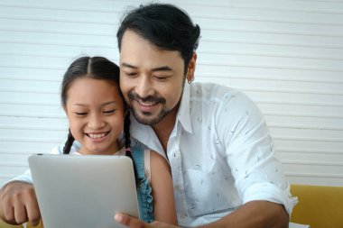 Asyalı baba tableti tut ve kızıyla birlikte gülümse..