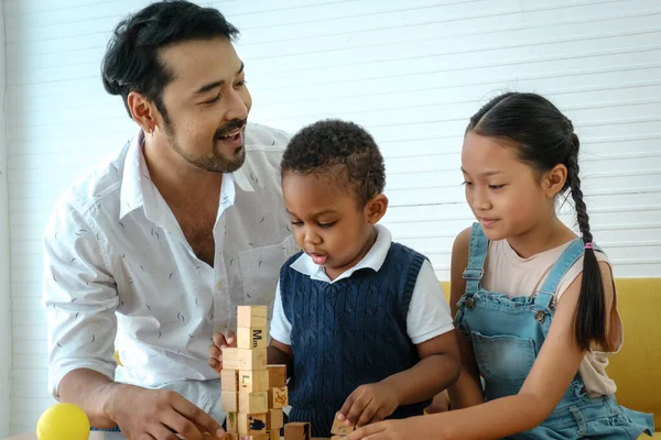 Asian family. Father with son and daughter spending times to play wooden toys together at home.