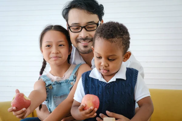 Asian happy family. Father looking his daughter and son eating apple and very happy.