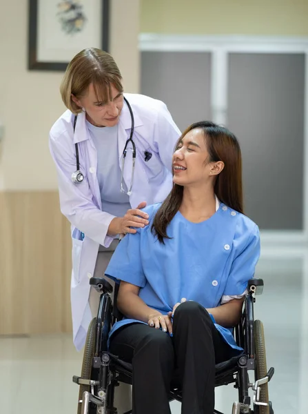 Doctor talk with patient sitting in wheelchair at hospital.