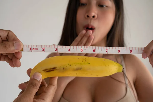 Sexy woman smiling with sweet banana and measurement tape.