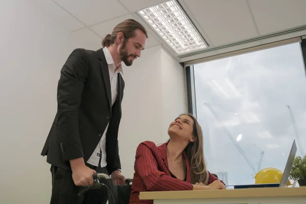 Colleagues helping disable friends in business office.