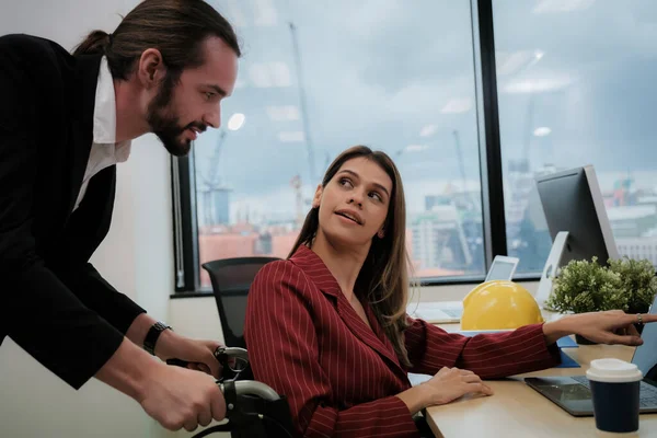 Colleagues helping disable friends in business office.