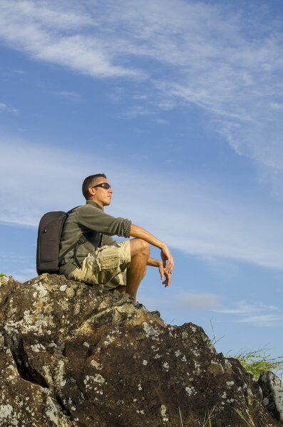 A Hiker Sits on a Large Boulder to Enjoy the View.