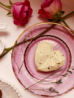 Güzel pembe güller ve beyaz arka planda kalp şeklinde bir pasta.