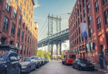 Manhattan ve Brooklyn arasındaki Manhattan Köprüsü, Dumbo, Brooklyn, New York 'ta güneşli bir günde iki tuğla bina tarafından çevrelenmiş dar bir ara sokaktan görülüyor.