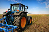 Velký traktor v poli - v pěkné modré slunečný den