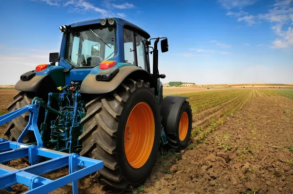 Ogromny traktor w dziedzinie - w piękny słoneczny dzień niebieski — Zdjęcie stockowe