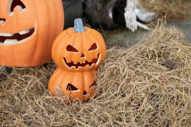 Komik yüzlü balkabağı, cadılar bayramı arka planında saman üstünde.