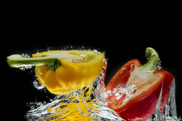 Splattered colored bell peppers splashed on a black background with a cut-out background.