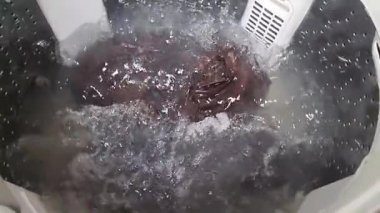 Çamaşır makinesi dönüyor ve çamaşır makinesinde çalışıyor..