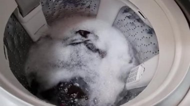 Çamaşır makinesi dönüyor ve çamaşır makinesinde çalışıyor..