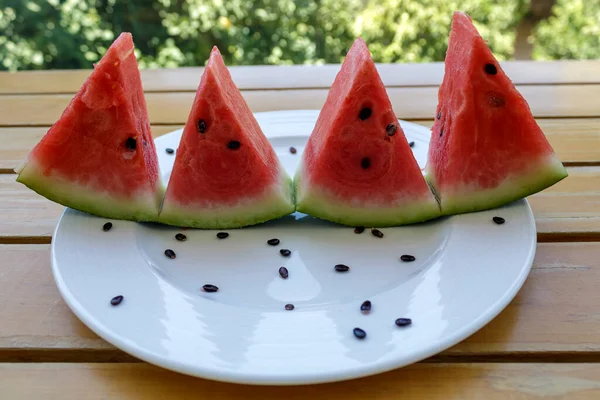 Vier Reife Dreieck Wassermelonenscheiben Mit Schwarzen Samen Auf Weißem Teller lizenzfreie Stockfotos