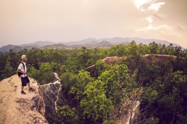 yürüyüş ve beyaz gömlek ve sırt çantası takmış dağlarda çalışan adam