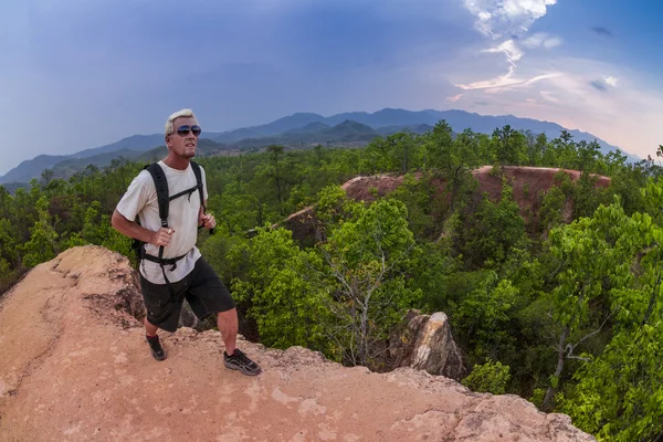 yürüyüş ve beyaz gömlek ve sırt çantası takmış dağlarda çalışan adam