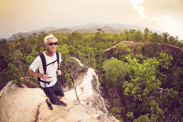 Man hiking and running in mountains wearing white shirt and backpack — Stock Photo, Image